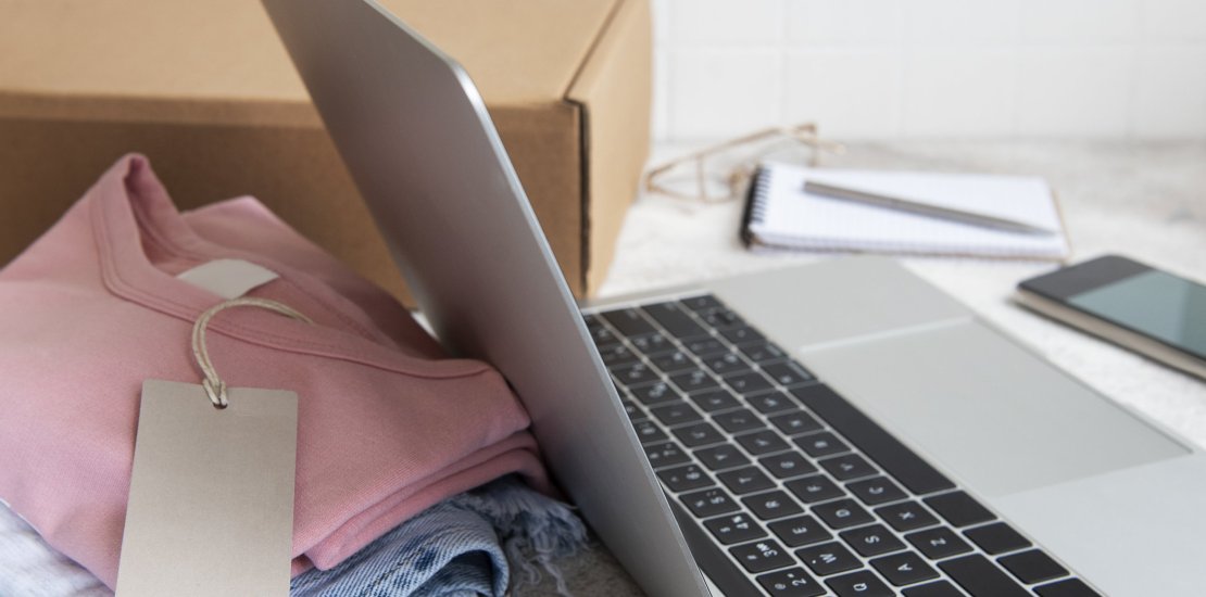 Online shopping concept. A laptop and a set of women's clothing in a cardboard box. Delivery of clothes.